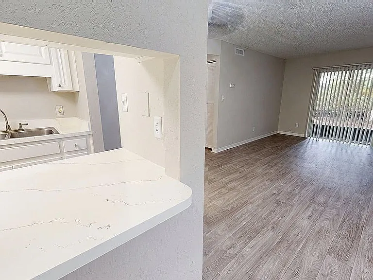 Bright and inviting open floor plan featuring a modern kitchen overlooking a spacious living room with large windows.