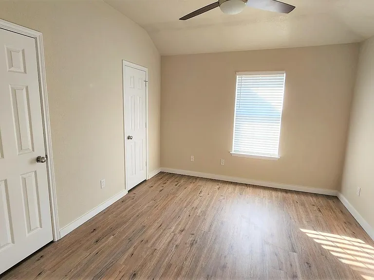 Large bedroom with two closests and a modern ceiling fan. Faux wood 2" blinds on the window.