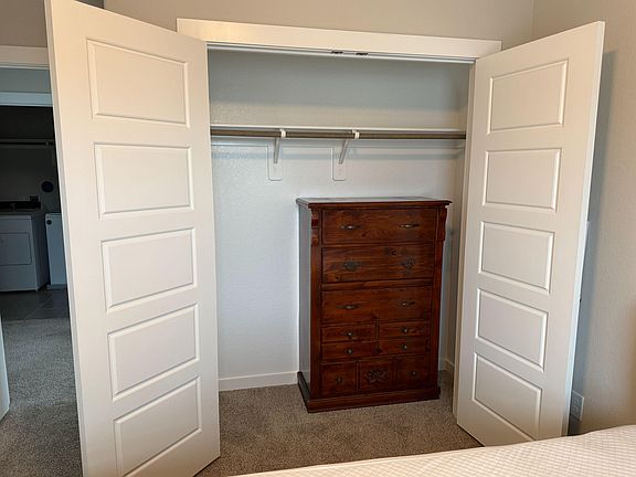 Bedroom closet with double doors, a full-length hanging rod, and an upper shelf for convenient everyday storage.