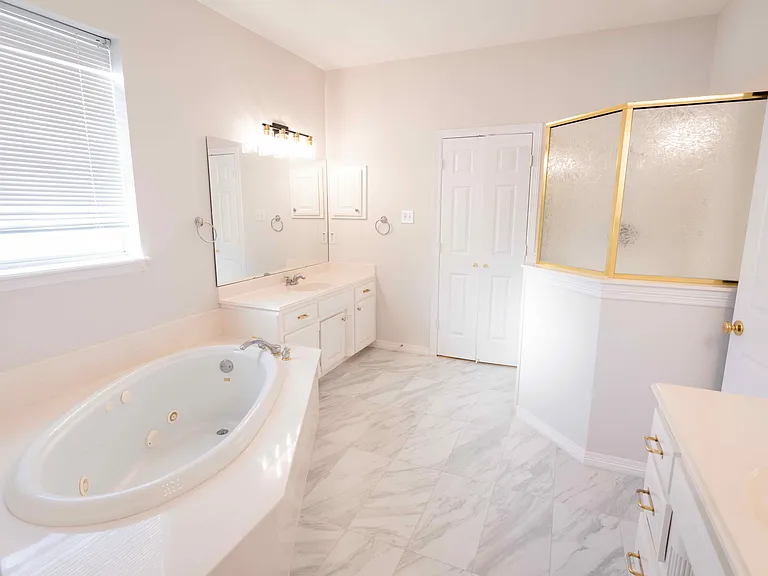 All white master bathroom with tub and stand in shower