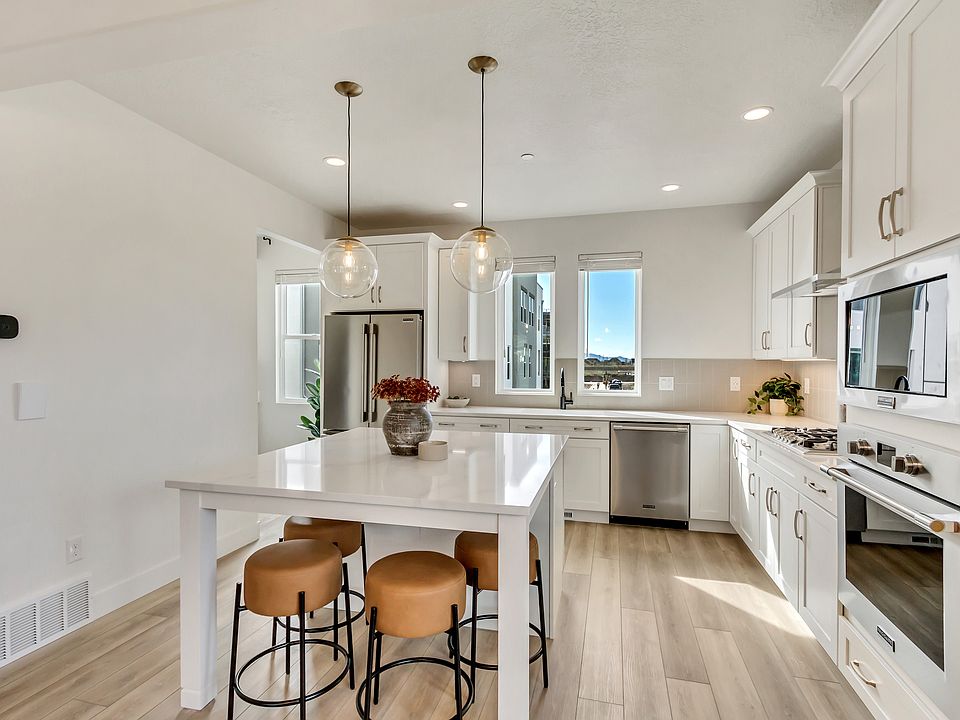 Modern kitchen with white cabinets, stainless steel appliances, a center island with three brown sto