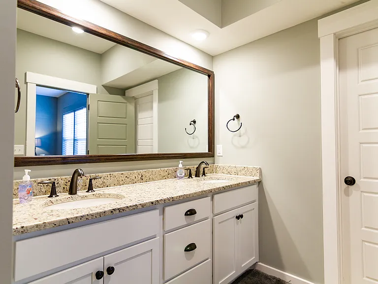 Primary bathroom with double vanity, water closet, and walk in shower.