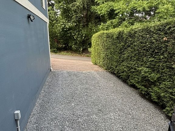 Gravel driveway with parking for 2 cars and steps leading to the apartment entrance.