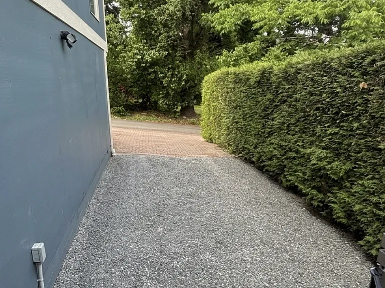 Gravel driveway with parking for 2 cars and steps leading to the apartment entrance.