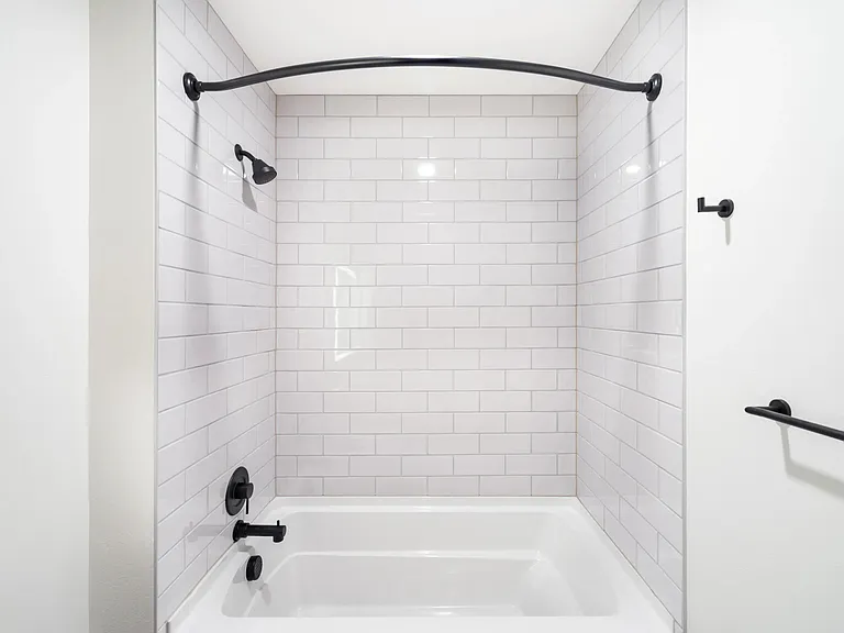 Bathroom with white tile surround, matte black fixtures, and a clean-lined tub and shower design suited to everyday comfort.