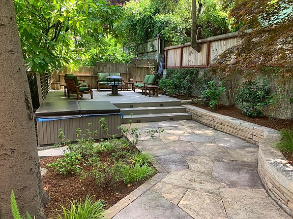 Spacious, landscaped backyard viewed from rear of the house. Yard includes deck with lounge seating, firepit, full-size Weber gas grill (not shows in this view) and hot tub. Yard is very private with no street noise and protected from wind by the house.