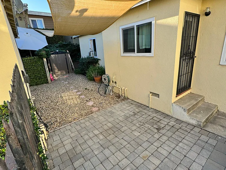 Private, gated, outdoor patio with seating area, garden, and space for outdoor storage