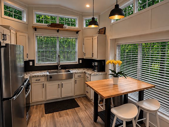 Fully furnished kitchen with farmhouse sink, microwave, gas stove, and dining area.