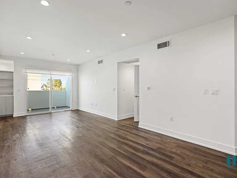 Spacious Living Room With Built-In Shelves, Vinyl Flooring, Recessed Lighting, and Patio