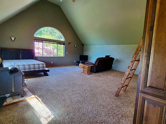 ADU Living Space - Armoire for clothes on the right. Wood stove on the left. Queen bed and living room furniture.