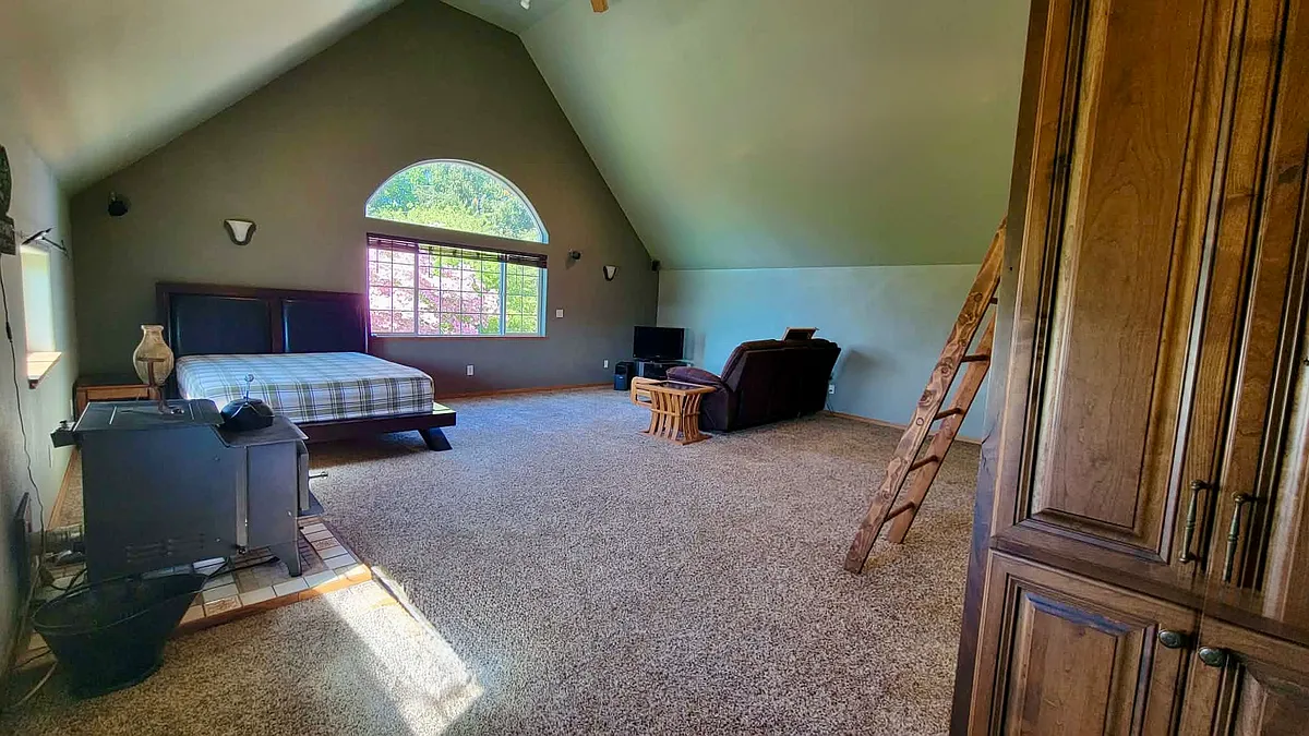 ADU Living Space - Armoire for clothes on the right. Wood stove on the left. Queen bed and living room furniture. - 9445 Wells Landing Rd