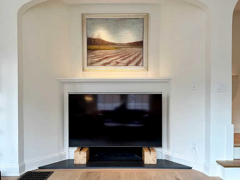 Living area alcove with decorative fireplace mantle and flat screen tv