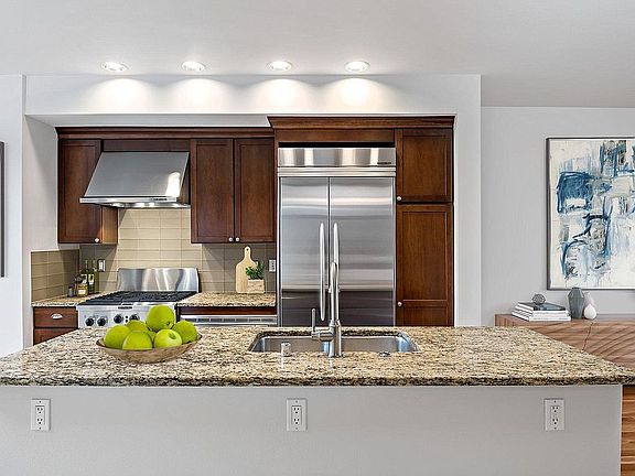 Gourmet kitchen with slab granite counters, glass tile backsplash, gas oven/range, and built-in refrigerator. Kitchen Aide appliance package. (second floor)