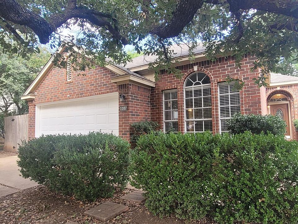 Charming brick home for rent, features include a two-car garage, large front windows, and lush landscaping with mature trees providing ample shade. Located in a quiet, friendly neighborhood