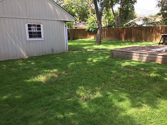 Spacious backyard with partial view of wood decked patio and oversized renovated garage.