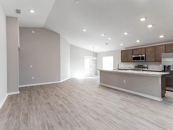 Enjoy an open living area with volume ceilings and low-maintenance vinyl plank flooring - New home f