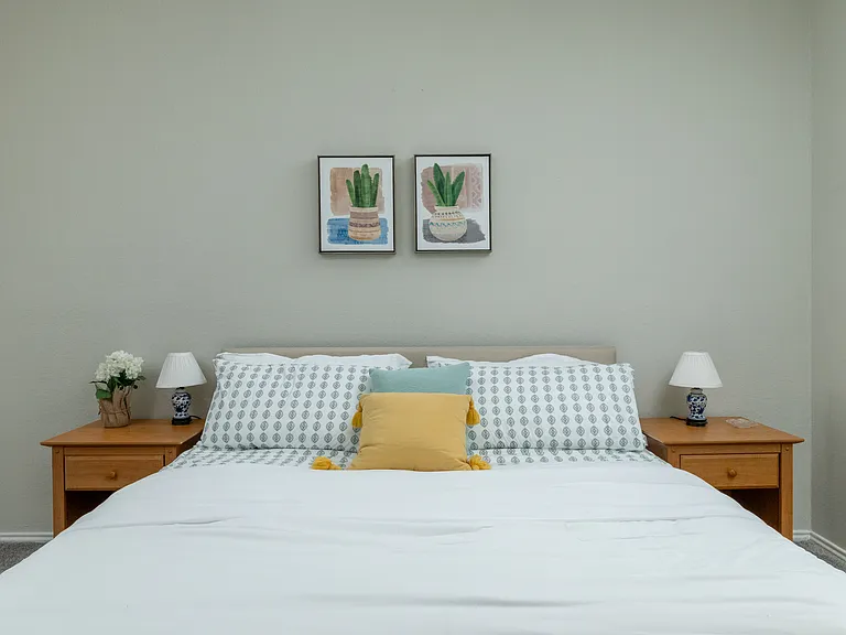 Primary bedroom on the first floor features a king bed, cozy chair, mirrored closet doors, and a ceiling fan for added comfort.