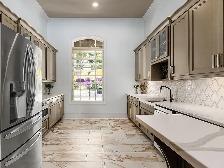 Luxurious modern kitchen with sleek stainless steel appliances, elegant marble flooring, and custom cabinetry, boasting abundant natural light.