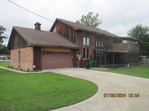 View of driveway, 2 car garage, large screened in patio 10 by 25 with Jacuzzi