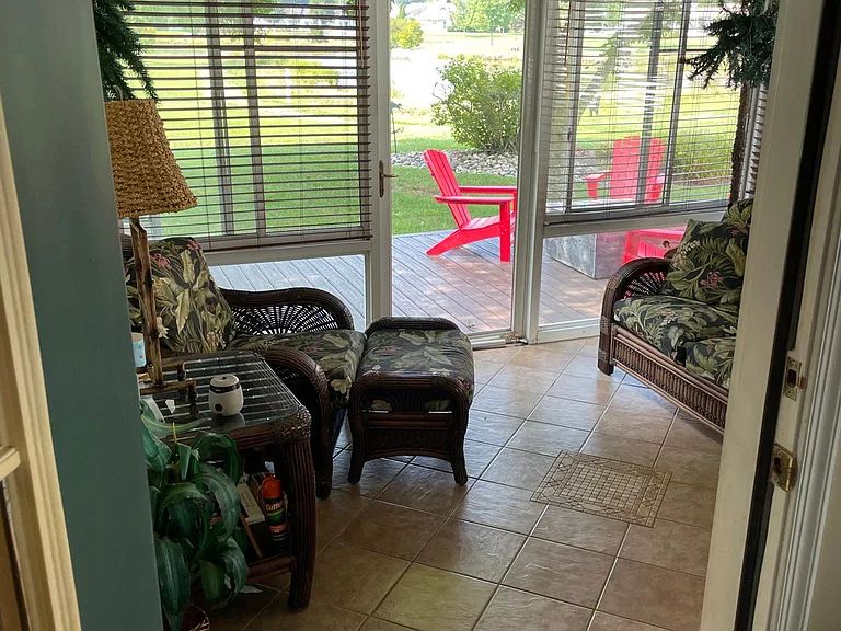 Sunroom with tile floor and views of the backyard, deck and pond.