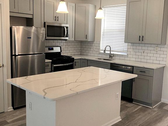 Renovated kitchen with quartz countertops and stainless steel appliances.