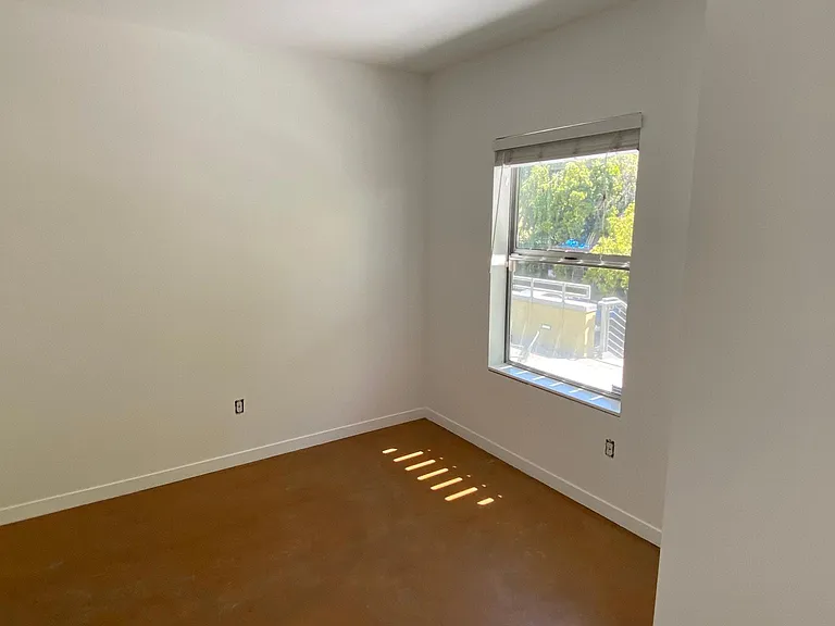 Bedroom 1, second view showing the window facing the communal patio.