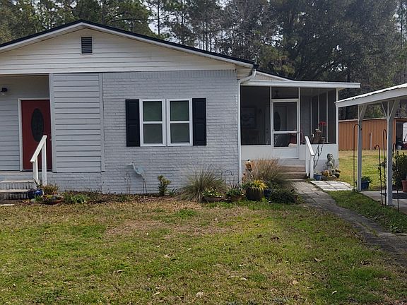 Side view showing screen porch entrance and carport on right