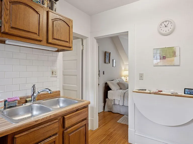 Another view of the good sized kitchen with ample storage, and well maintained hardwood floors. Kitchen and bathroom are right off the bedroom for easy access. Includes east-facing window for beautiful, soft morning light to accompany your coffee or tea.