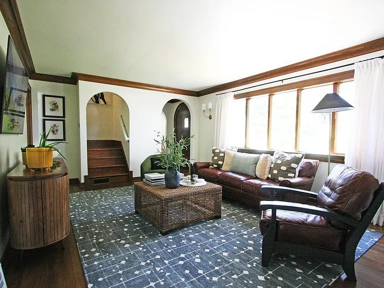 The staircase leads to two upstairs bedrooms and a full bathroom. The front door opens to a small, private front yard.