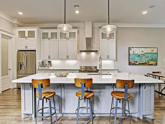 Kitchen is bright and open with custom 42â custom cabinets with under-mount lighting, granite countertops with mosaic stone backsplash, Bertazzoni stove, Bosch dishwasher, and an oversized breakfast bar.