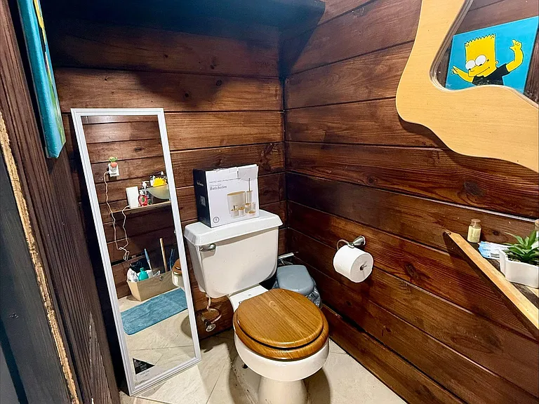 Half bath with wood-paneled walls, tiled flooring, and storage shelving for everyday essentials.