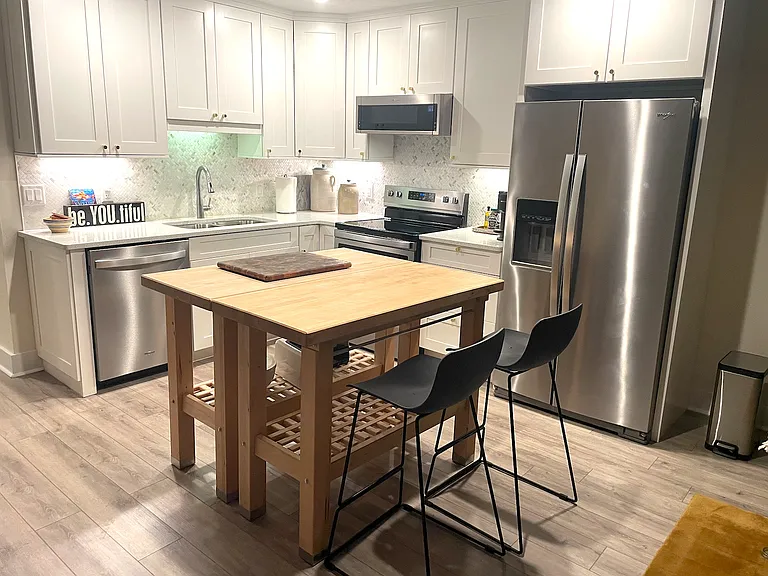 Kitchen layout, including bright white cupboards & butcher block island