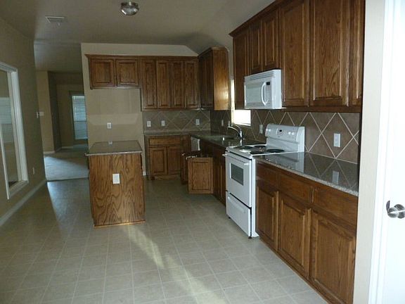 Kitchen with Island and custom ash cabinets. Granite counter