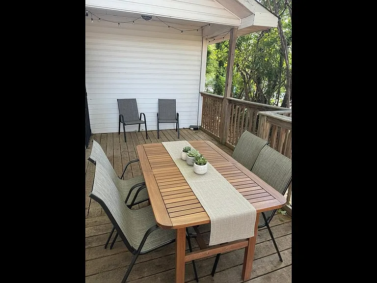 Partially covered wooden deck with outdoor dining set, for relaxing meals outside.