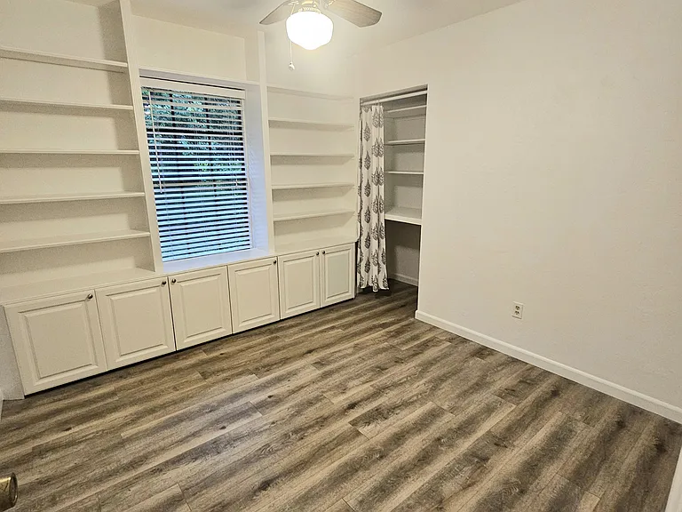 Small bedroom/office with built-in shelving and cabinets