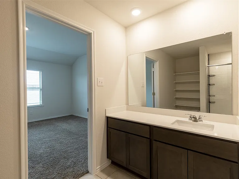 Bathroom vanity featuring an integrated sink, a wide mirror, and dark wood-finish cabinetry