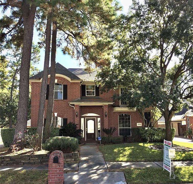 Front view shows attractive brick elevation, landscaping, and mature trees for additional shade.