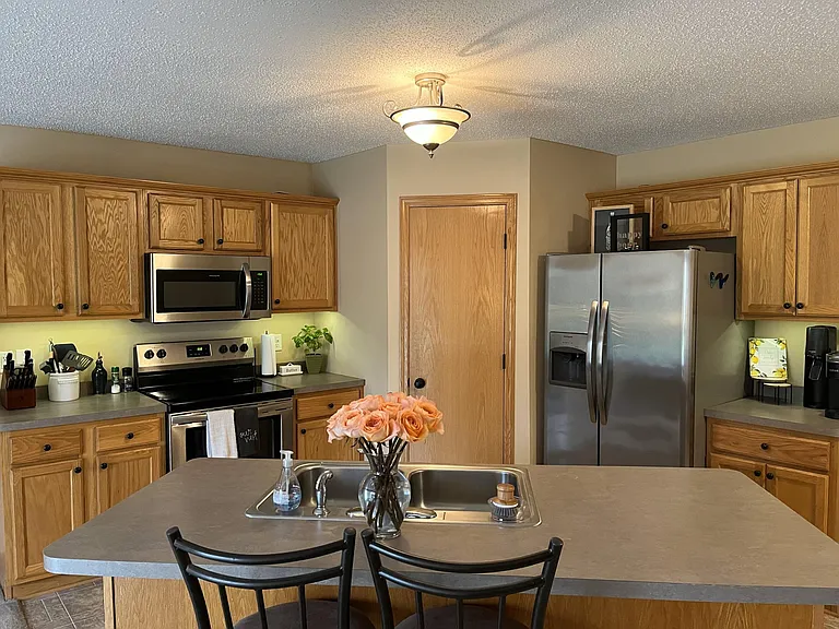 Lower level kitchen with stainless steel appliances, open to living and dining area.