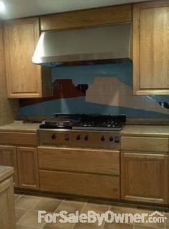 Custom tile backsplash over the gas cooktop and continuing around the kitchen.