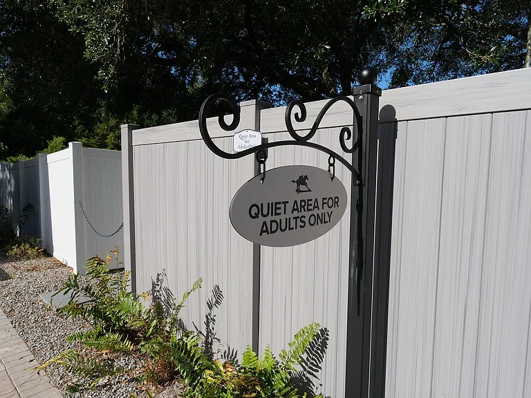 Tranquil outdoor area with a sign for 'Quiet Area for Adults Only,' surrounded by lush greenery and wooden fencing.