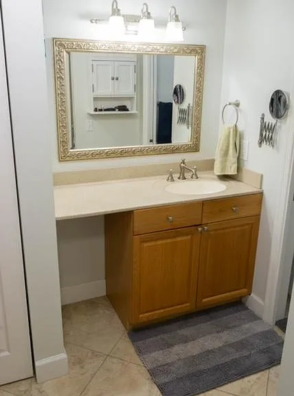 Bathroom vanity has a spacious counter and small wall cabinet for added storage.