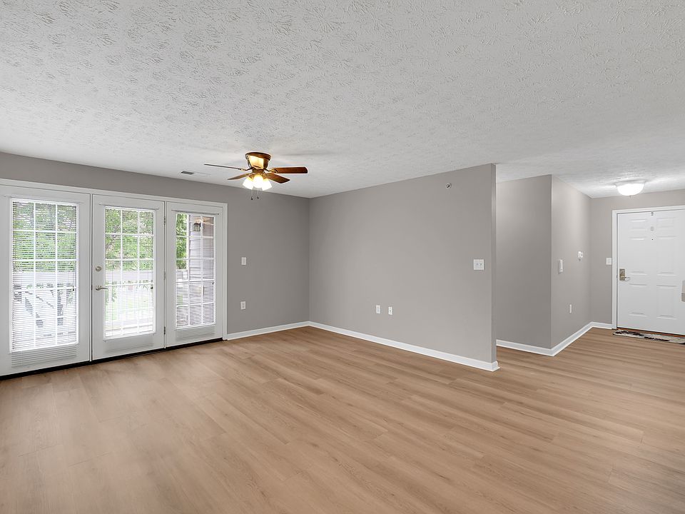 View of living area and large glass doors leading to private balcony. Ceiling fan are visable.