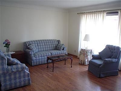 CHARMING LIVING ROOM WITH LAMINATE WOOD FLOORING AND A LARGE BAY WINDOW.