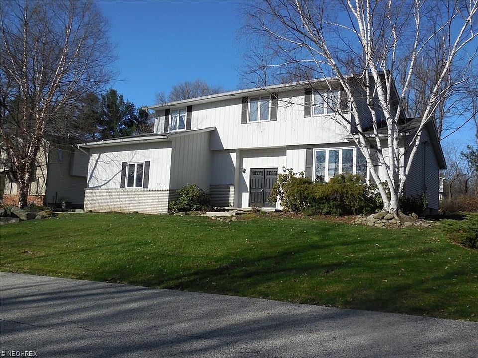 Beautiful Contemporary Colonial sits on a treed wood yard.