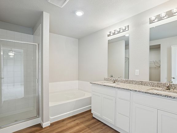 The master bathroom has a dual sink vanity and a soaking tub and step in shower.