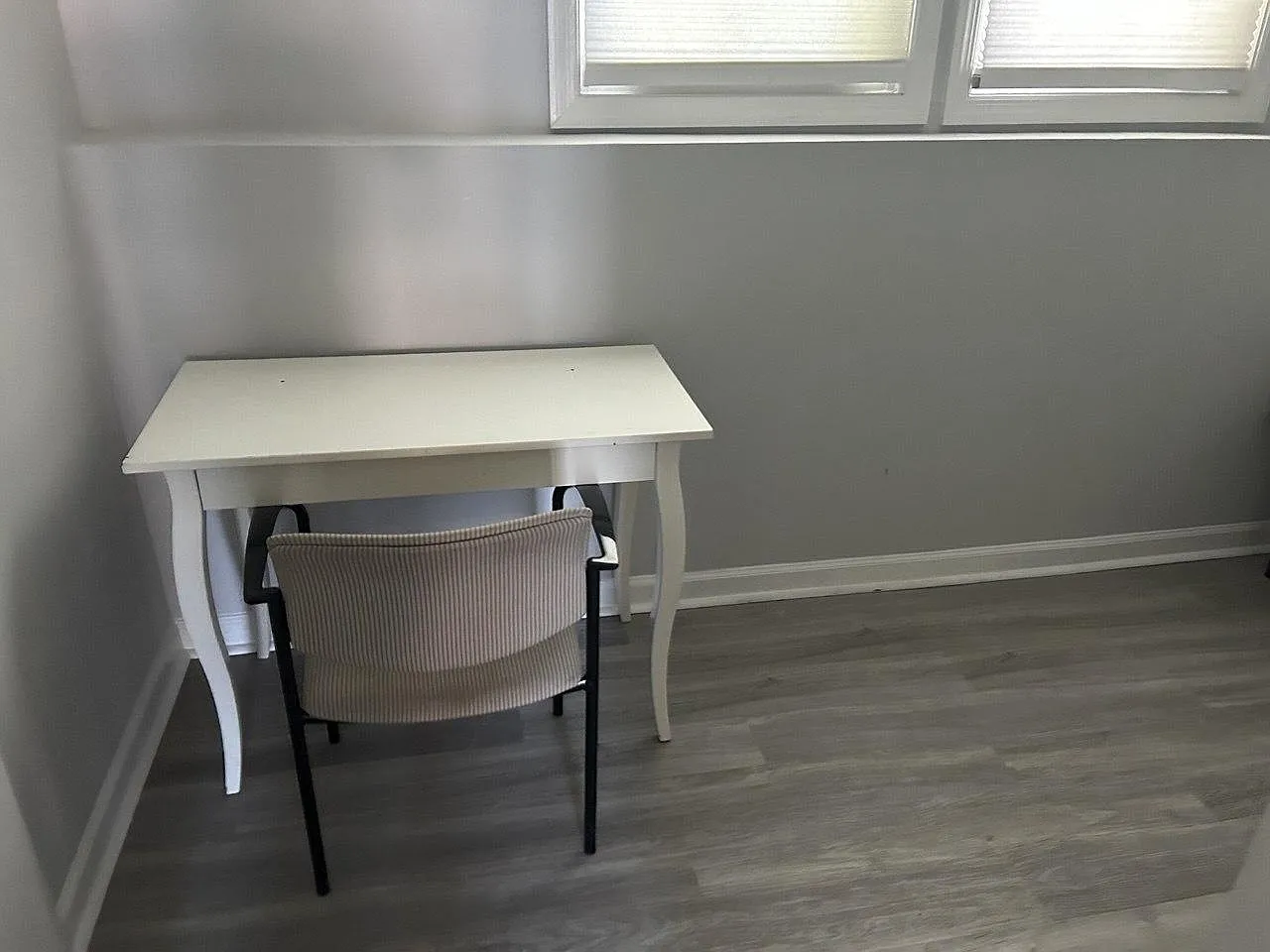 Work-from-home nook with a compact desk and chair, set beneath windows and finished with durable plank-style flooring.