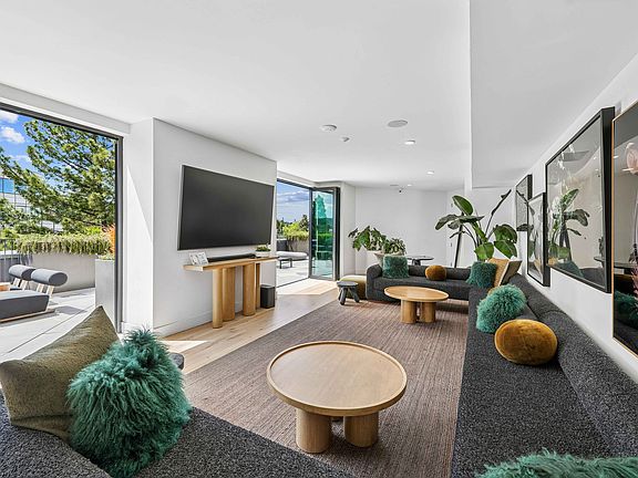 Bright and modern living room with stylish furniture, lush green plants, and a seamless flow to a sunlit outdoor patio.