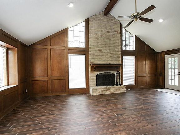 This Living Room is uniquely charming, with vaulted ceilings, brick fireplace, rich wood paneled walls, and French doors leading to the large back yard.