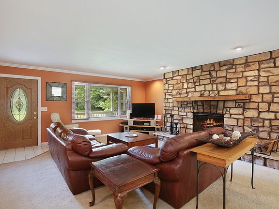 Living room has large stone gas log fireplace.