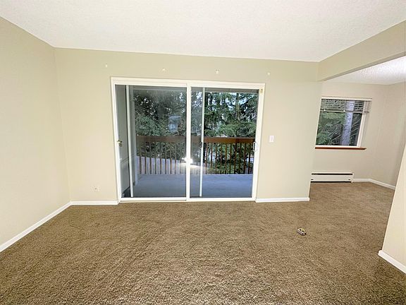 Large living room with view of large deck. Natural surroundings for pleasant ambiance.